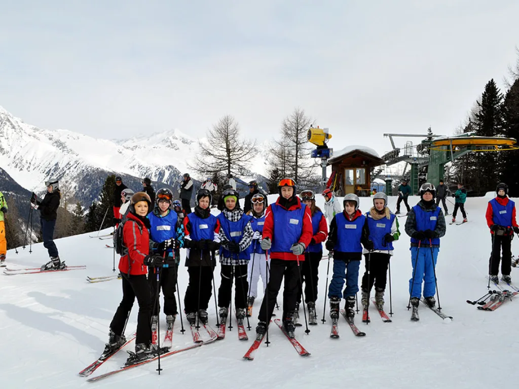 Skigruppe steht in einer Reihe vor der Bergstation.